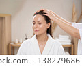 Elegant woman with closed eyes receiving a therapeutic head massage in a spa 138279686
