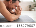 Middle aged man performing a childs pose on a yoga mat with closed eyes 138279687