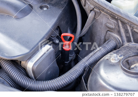 Bright red dipstick is positioned within the engine compartment, ready for a quick check to ensure oil levels are just right after driving 138279707