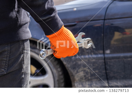 A dedicated mechanic stands confidently, clutching a wrench, ready to solve car problems in a bustling garage under bright sunlight A dedicated mechanic stands confidently, clutching a wrench, ready to solve car problems in a bustling garage under bright sunlight 138279713