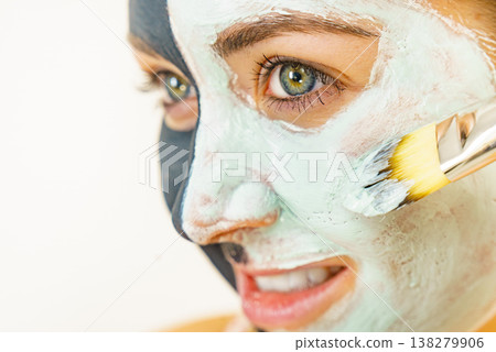 Female applying green mud facial mask Female applying green mud facial mask 138279906