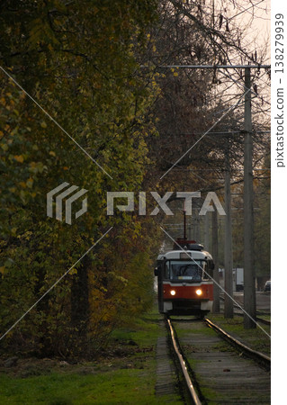 Tram urban public transport rides on rails with green grass and trees. transportation of passengers. Tram urban public transport rides on rails with green grass and trees. transportation of passengers. 138279939