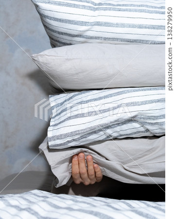 woman holds stack of pillows with her hands while sitting on the bed. rest and restful sleep. woman holds stack of pillows with her hands while sitting on the bed. rest and restful sleep. 138279950