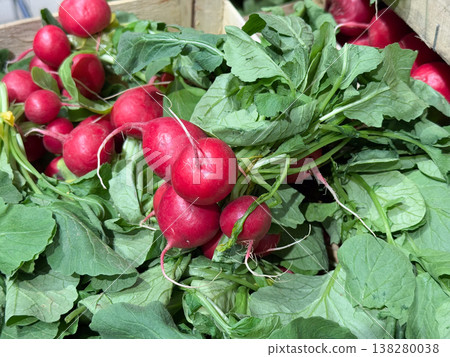 Radish bunch arranged in wooden crate with fresh leaves and natural surface detail. Seasonal harvest, organic farming, vegetable retail, healthy nutrition and local market produce presentation 138280038