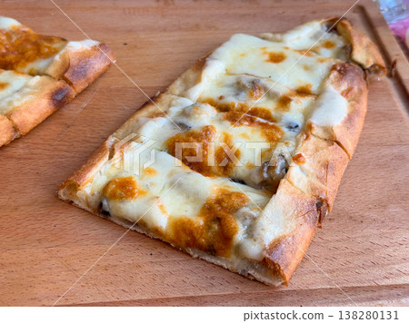Closeup of a single cheese and mushroom pide slice with browned crust on a wooden board. Baked menu specialty, artisan flatbread detail and savory cafe food concept for restaurant promotion Closeup of a single cheese and mushroom pide slice with browned crust on a wooden board. Baked menu specialty, artisan flatbread detail and savory cafe food concept for restaurant promotion 138280131