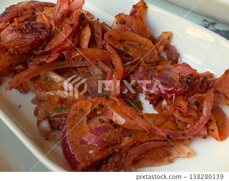 Close-up seasoned red onion salad served in a white dish as a traditional kebab accompaniment. Turkish meze plating, savory restaurant side and marinated vegetable garnish for grilled meat meals 138280139