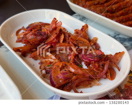 Seasoned red onion salad served in a white dish as a traditional kebab accompaniment. Turkish meze plating, savory restaurant side and marinated vegetable garnish for grilled meat meals Seasoned red onion salad served in a white dish as a traditional kebab accompaniment. Turkish meze plating, savory restaurant side and marinated vegetable garnish for grilled meat meals 138280143