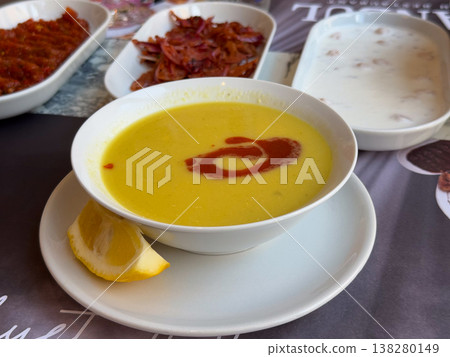 Creamy lentil soup served with paprika butter swirl and lemon on a white plate. Traditional Turkish comfort food, restaurant starter presentation and warm nourishing meal concept Creamy lentil soup served with paprika butter swirl and lemon on a white plate. Traditional Turkish comfort food, restaurant starter presentation and warm nourishing meal concept 138280149