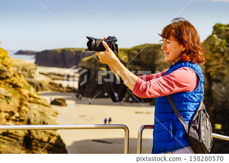 Woman with camera at Cathedral Beach in Spain. Woman with camera at Cathedral Beach in Spain. 138280570
