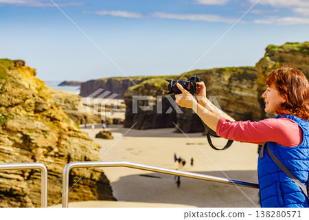 Woman with camera at Cathedral Beach in Spain. Woman with camera at Cathedral Beach in Spain. 138280571