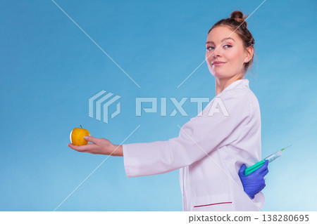 Scientist doctor with apple and syringe. GM Food. 138280695