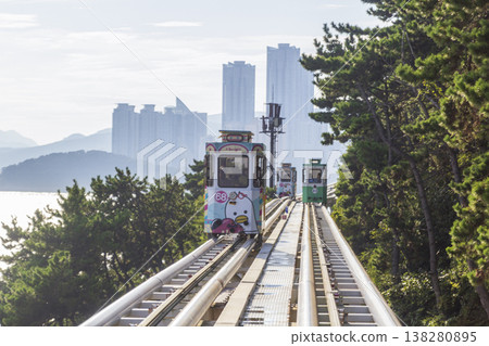 Colorful oceanfront capsule cars travel along an elevated coastal rail, offering scenic seaside views and a relaxed tourism experience over the water. High quality photo 138280895