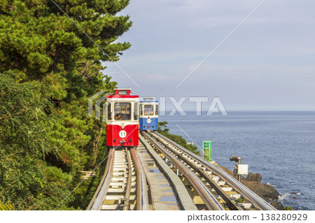 Colorful oceanfront capsule cars travel along an elevated coastal rail, offering scenic seaside views and a relaxed tourism experience over the water. High quality photo 138280929