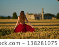Woman rye field red dress. Happy woman in a long red dress in a beautiful cornfield. Old caste ruins in the background 138281075