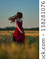 Woman rye field red dress. Happy woman in a long red dress in a beautiful cornfield. Old caste ruins in the background 138281076