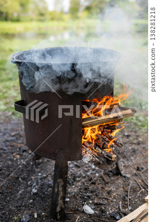 Traditional Cooking Over Open Fire in a Countryside Setting With Smoke and Flames Wafting From the Pot Traditional Cooking Over Open Fire in a Countryside Setting With Smoke and Flames Wafting From the Pot 138281218
