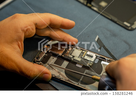 Expert Hands Perform Phone Repair on a Disassembled Device in a Workshop Setting During Daylight Hours Expert Hands Perform Phone Repair on a Disassembled Device in a Workshop Setting During Daylight Hours 138281246