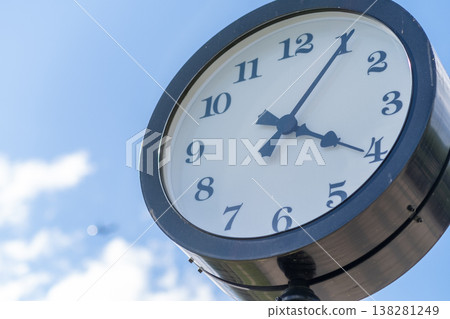Classic Clock Under a Clear Blue Sky Near a Park, Showcasing the Time Just Before Four Oclock in the Afternoon 138281249