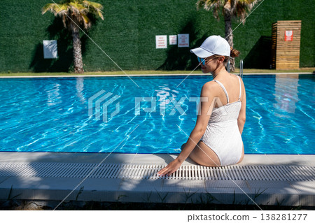 Enjoying a Sunny Day by the Poolside in a Stylish Swimsuit With Palms in the Background on a Bright Afternoon 138281277