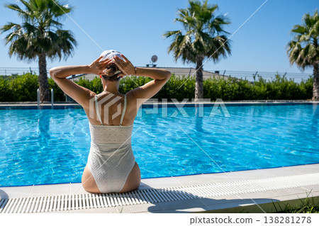 Relaxing by the Poolside During a Sunny Day in a Tropical Location With Palm Trees and Clear Blue Water Relaxing by the Poolside During a Sunny Day in a Tropical Location With Palm Trees and Clear Blue Water 138281278
