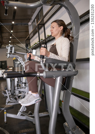 Woman Exercising on Gym Equipment in Modern Fitness Center While Focusing on Leg Strength Training Woman Exercising on Gym Equipment in Modern Fitness Center While Focusing on Leg Strength Training 138281280