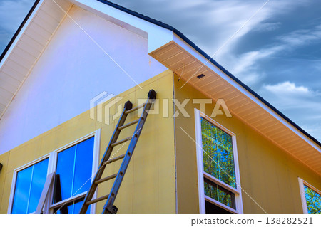 Workers are painting fiber siding side of house using ladder after fiber siding Workers are painting fiber siding side of house using ladder after fiber siding 138282521