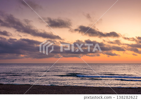 sunrise over the sea. beach landscape in golden glow. morning sky with purple clouds above horizon. scenery with calm waves. tranquil seascape wallpaper for summer vacation sunrise over the sea. beach landscape in golden glow. morning sky with purple clouds above horizon. scenery with calm waves. tranquil seascape wallpaper for summer vacation 138282622