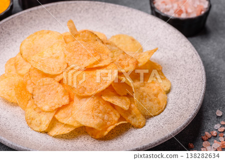 Crispy potato chips, golden slices seasoned with salt and spices. Potato chips Crispy potato chips, golden slices seasoned with salt and spices. Potato chips 138282634