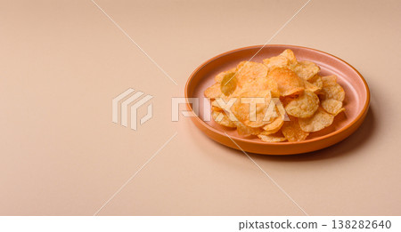 Crispy potato chips, golden slices seasoned with salt and spices. Potato chips Crispy potato chips, golden slices seasoned with salt and spices. Potato chips 138282640
