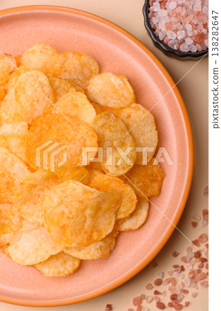 Crispy potato chips, golden slices seasoned with salt and spices. Potato chips Crispy potato chips, golden slices seasoned with salt and spices. Potato chips 138282647