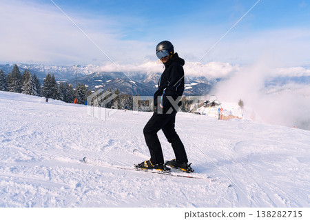 Male skier standing on snowy mountain slope with alpine landscape Male skier standing on snowy mountain slope with alpine landscape 138282715