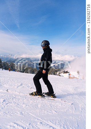Male skier standing on snowy mountain slope with alpine landscape Male skier standing on snowy mountain slope with alpine landscape 138282716