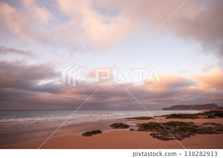 Tranquil coastal scene of a sandy beach at sunset with pink clouds 138282913