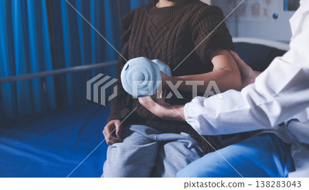 Old woman training with physiotherapist using dumbbells at home. Therapist assisting senior woman with exercises in nursing home. Elderly patient using dumbbells with outstretched arms. 138283043