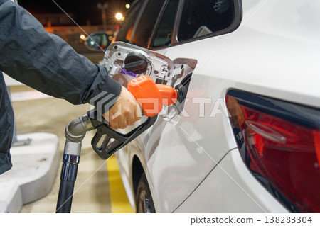 A nighttime refueling scene that evokes images of rising gasoline prices and household budget conservation. 138283304