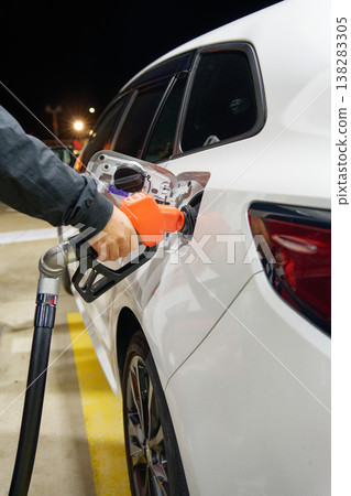 A vertical composition depicting a nighttime refueling scene, symbolizing rising gasoline prices and household budget conservation. A vertical composition depicting a nighttime refueling scene, symbolizing rising gasoline prices and household budget conservation. 138283305