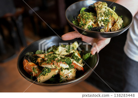 Chef serving gourmet seafood dishes with herbs and sauce presentation 138283448