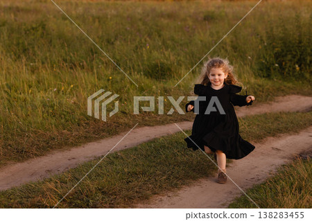 Little girl running on rural dirt road in meadow at sunset with copy space Little girl running on rural dirt road in meadow at sunset with copy space 138283455