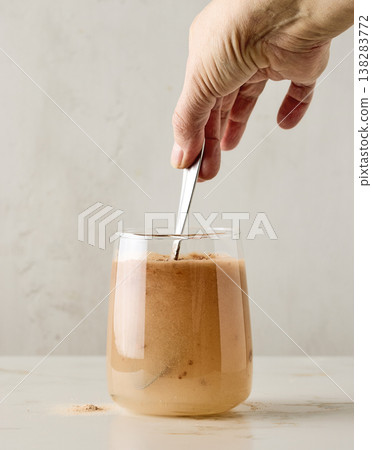 Protein powder mixed in water with spoon in glass on light kitchen background 138283772