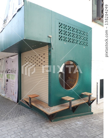 A building with green exterior walls and round windows; a simple shop exterior design. A building with green exterior walls and round windows; a simple shop exterior design. 138284249