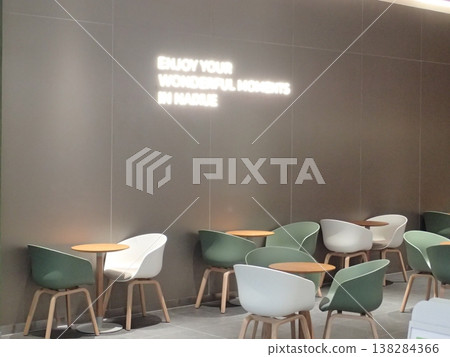 現代化的咖啡廳空間，牆上掛著品牌標誌，擺放著簡單的桌椅。 138284366
