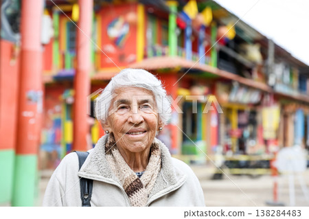Happy senior lifestyle concept. Senior woman at the central square of the beautiful small town of Raquira. The city of pots in Colombia. 138284483