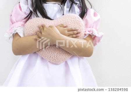 一個穿著女僕裝、抱著心型毛絨玩具的5歲日本女孩(沒有露臉)。 一個穿著女僕裝、抱著心型毛絨玩具的5歲日本女孩(沒有露臉)。 138284598