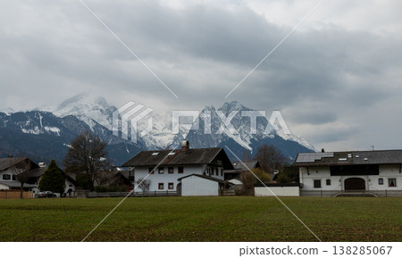 Alpine village houses with dramatic cloudy mountain backdrop Alpine village houses with dramatic cloudy mountain backdrop 138285067
