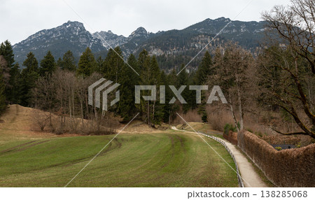 Narrow path through meadow toward forest and mountain ridge 138285068