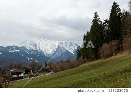 Mountain village hillside with cloudy alpine peaks Mountain village hillside with cloudy alpine peaks 138285070