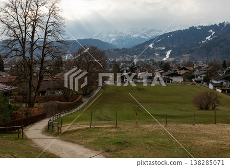 Path descending toward alpine town under dramatic sky Path descending toward alpine town under dramatic sky 138285071