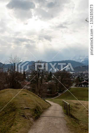 Sun rays over alpine town and distant snowy mountains Sun rays over alpine town and distant snowy mountains 138285073