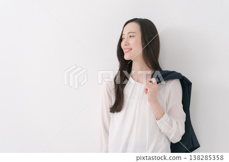 A woman in a suit with a jacket draped over her shoulders. A woman in a suit with a jacket draped over her shoulders. 138285358