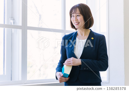 A female lawyer stands by the window at a law firm. A female lawyer stands by the window at a law firm. 138285378